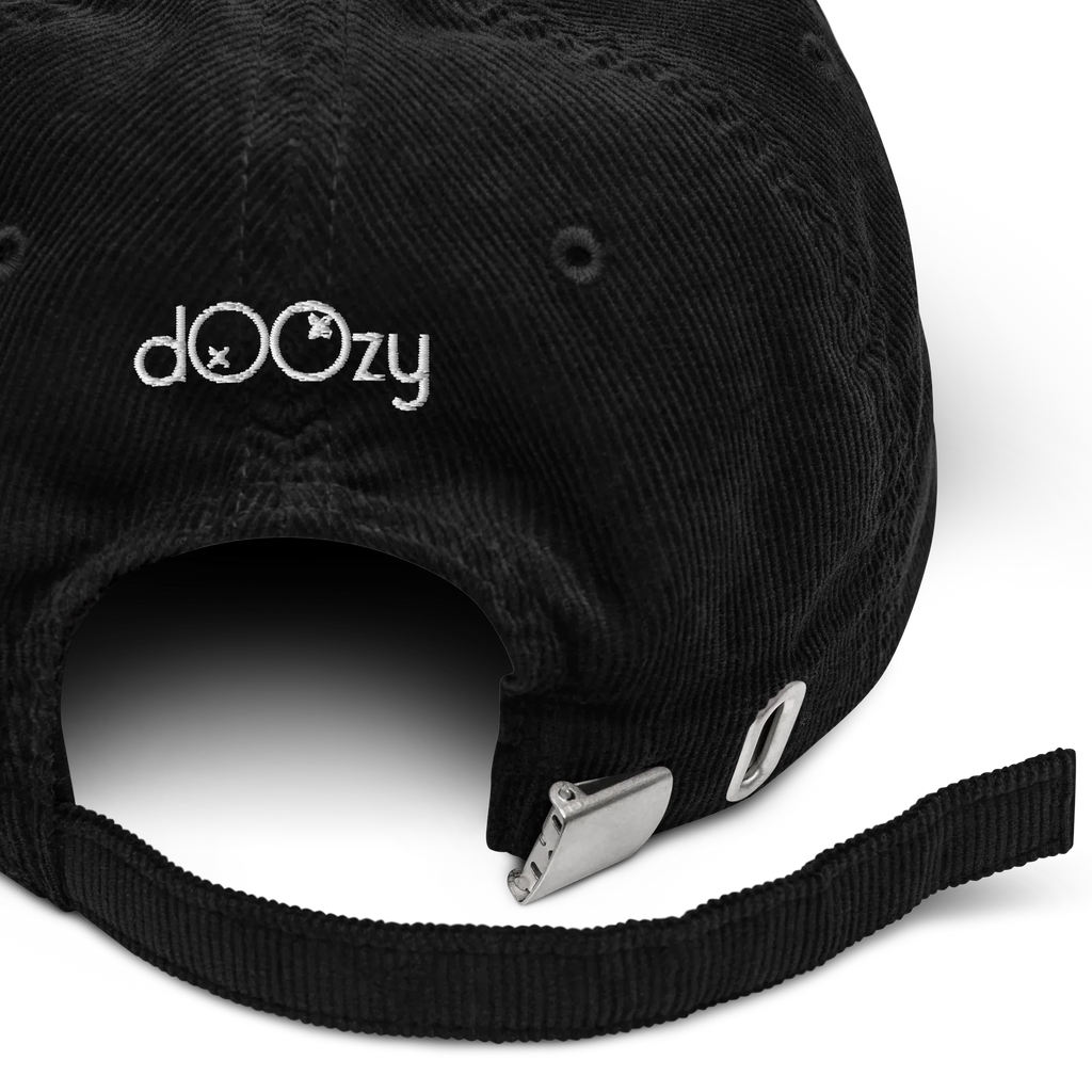 Detalle de gorra negra de pana Doozy Headwear con cierre ajustable metálico y logo bordado.
